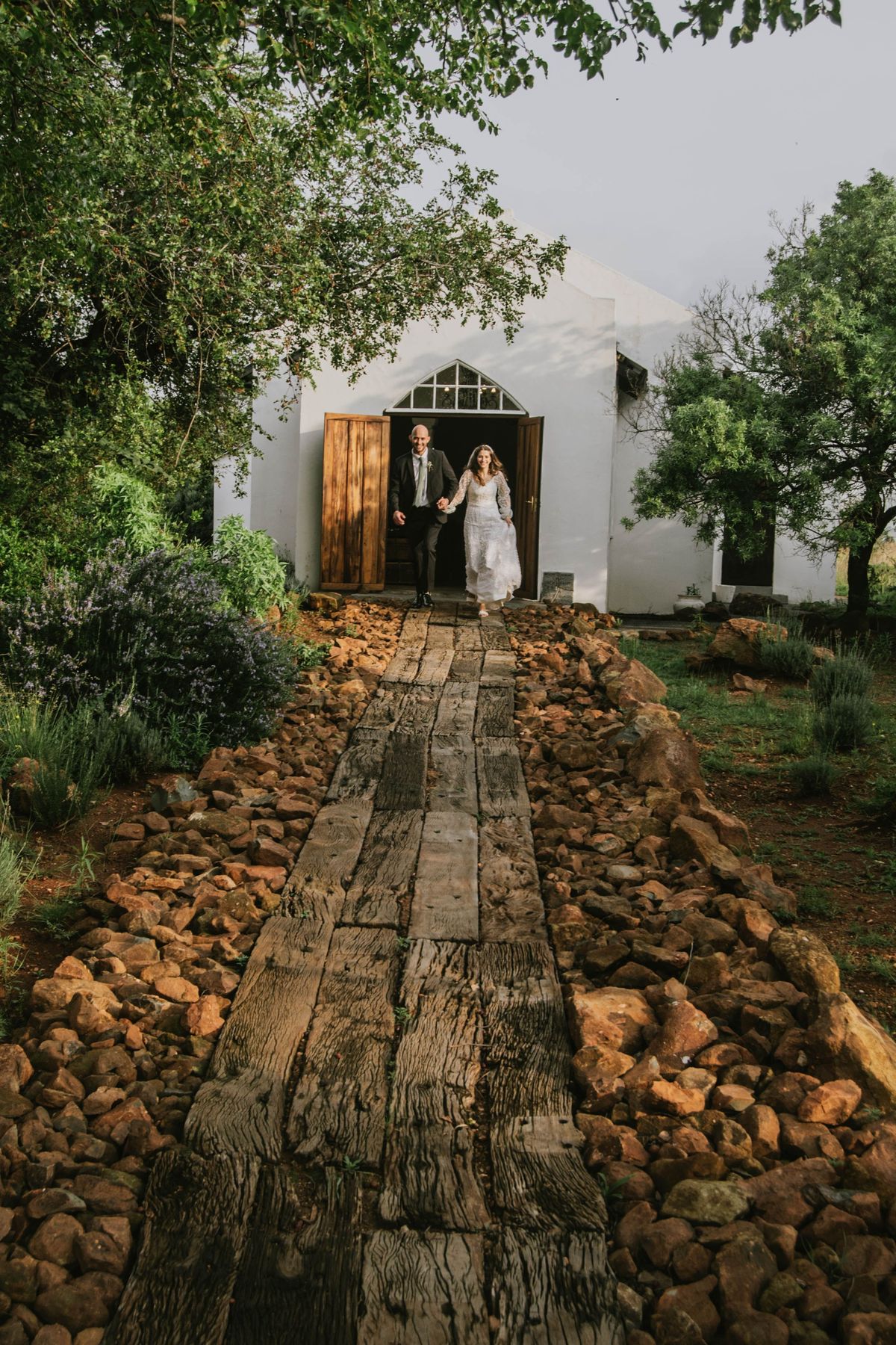 Newlyweds walking hand-in-hand from garden chapel