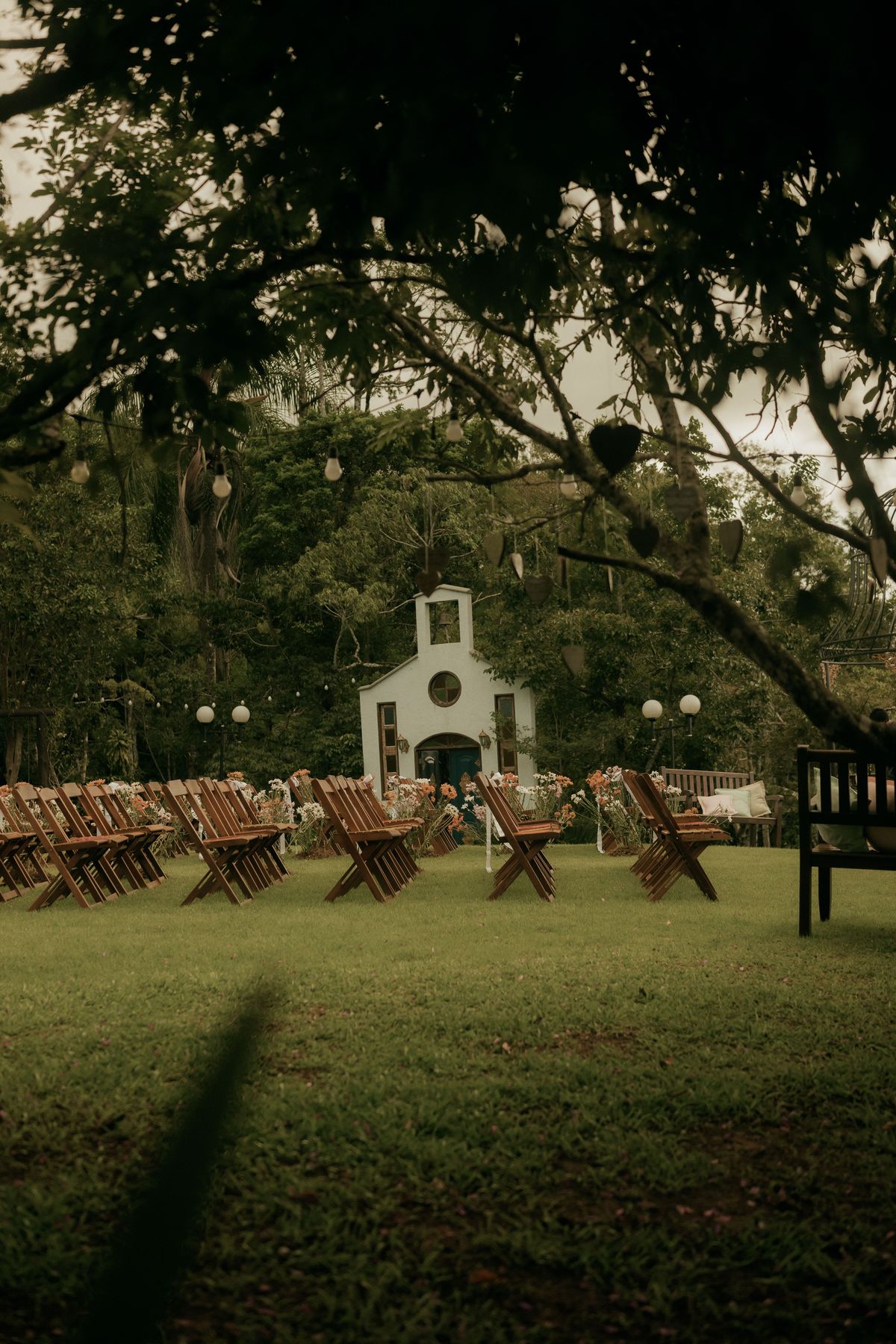 Outdoor garden ceremony setup with white chairs and floral arch